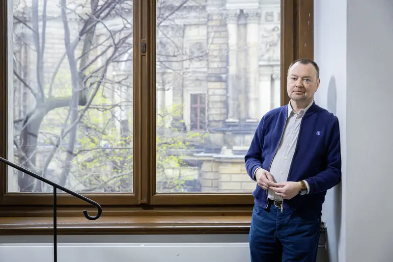 Mann an einer Wand vor einem Fenster lehnend